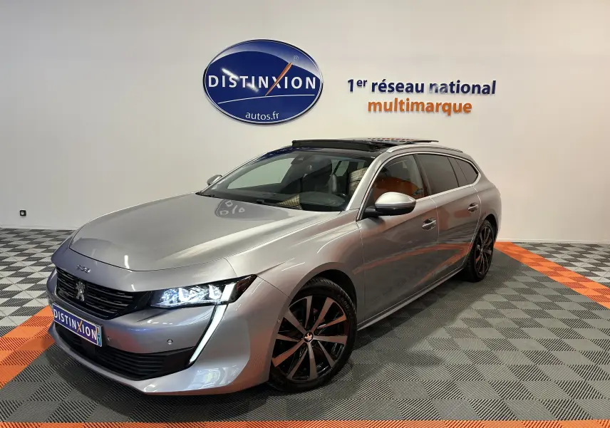 Peugeot 508 SW gris Platinium en 3/4 avant droit, avec toit ouvrant et jantes noires bicolores.