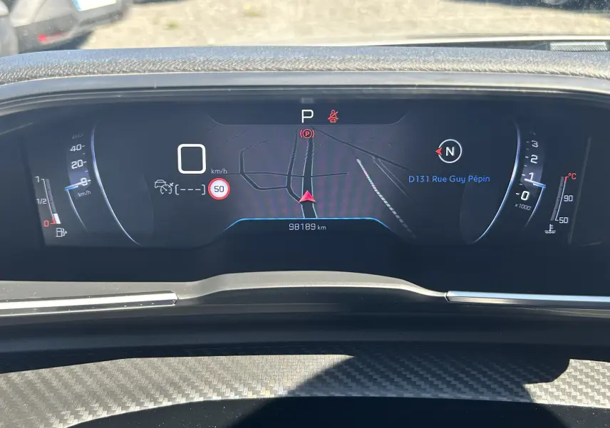 Vue rapprochée du tableau de bord numérique du Peugeot 508 SW affichant la navigation et les indicateurs de vitesse et température.