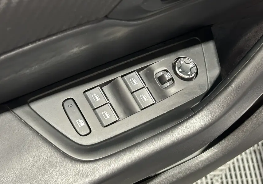 Gros plan sur les commandes de lève-vitres et réglage des rétroviseurs côté conducteur d’un Peugeot 508 SW gris Platinium.