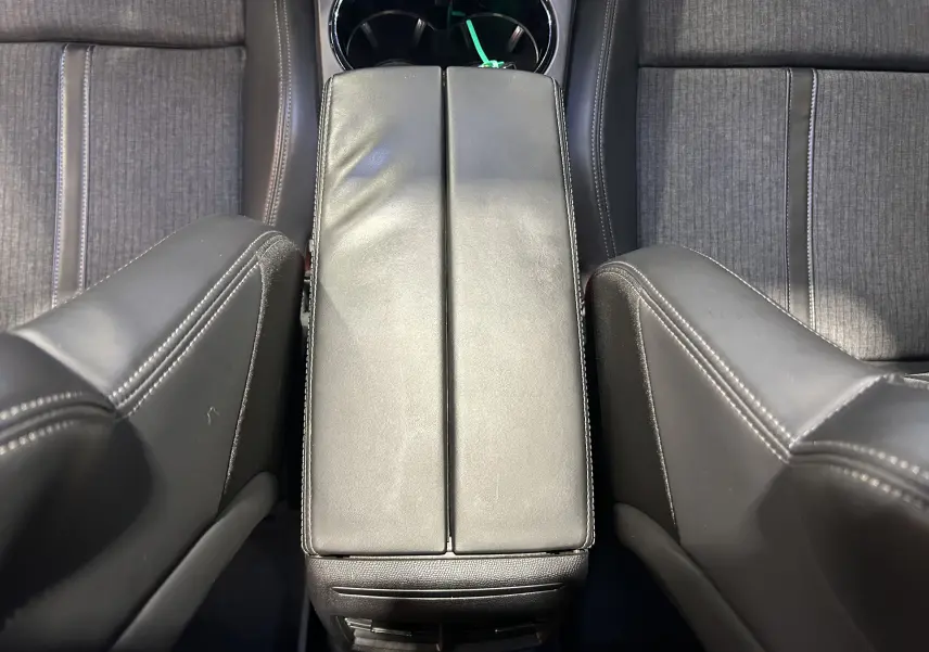 Vue plongeante sur l'accoudoir central en cuir noir et les sièges avant en tissu gris du Peugeot 508 SW 2019.