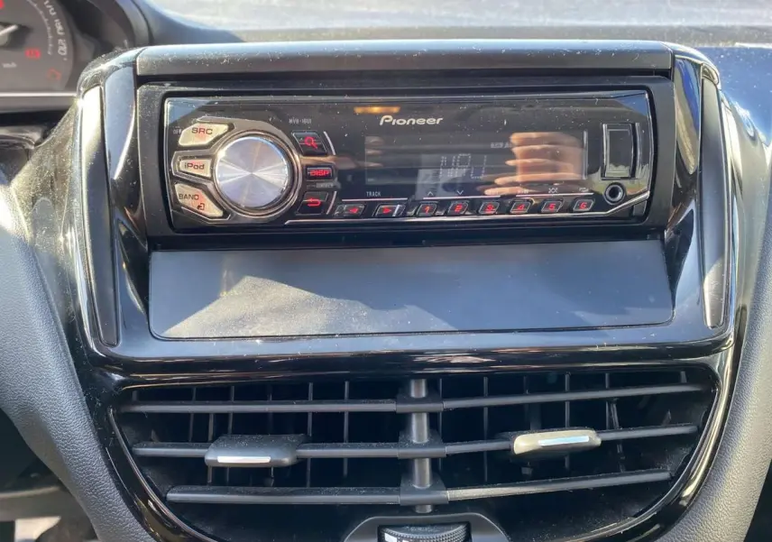 Vue rapprochée de l’autoradio Pioneer noir intégré au tableau de bord d’une Peugeot 208 noire.