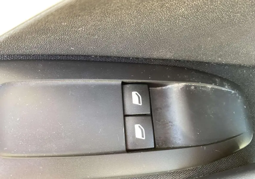 Gros plan sur les commandes de lève-vitres électriques côté conducteur de la Peugeot 208 noire de 2015.