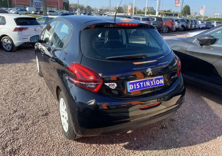 Peugeot 208 noire vue 3/4 arrière droit, avec jantes blanches et feux arrière distinctifs en forme de griffes.
