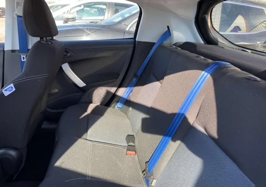 Vue intérieure côté droit montrant la banquette arrière noire avec ceintures de sécurité bleues sur Peugeot 208 2015.