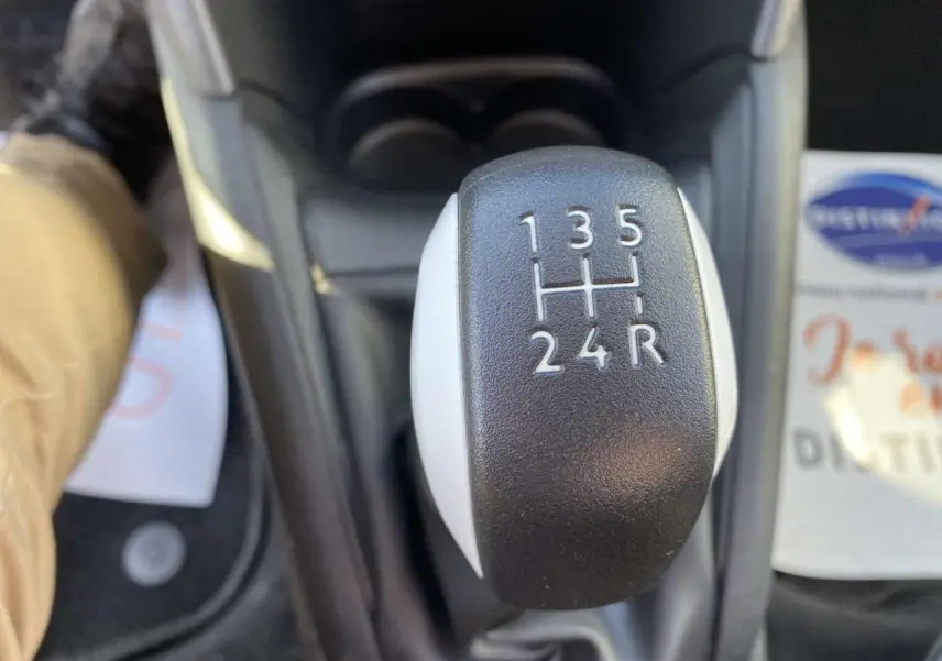 Gros plan sur le levier de vitesses manuel noir et blanc de la Peugeot 208 essence, vue intérieure centrée.