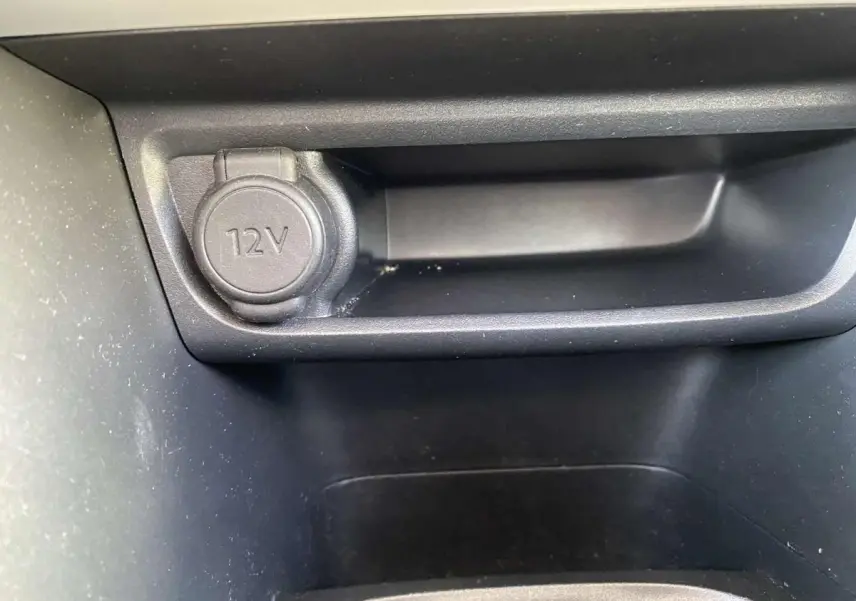 Gros plan sur la prise 12V noire dans le compartiment intérieur du Peugeot 208 noir, version Like 2015.