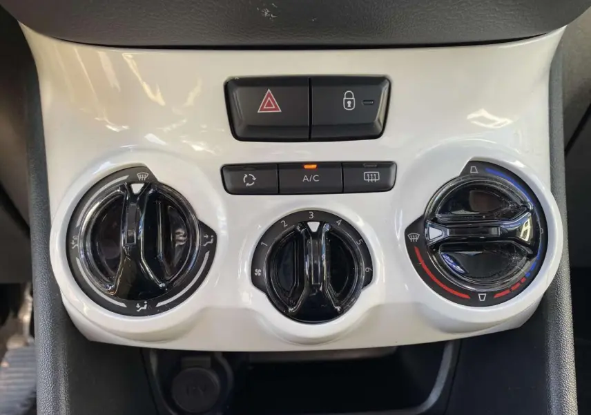 Vue rapprochée des commandes de climatisation et des boutons de sécurité sur la console centrale blanche d'une Peugeot 208 noire.