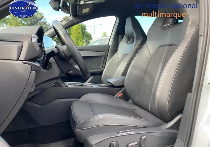 Vue intérieure côté conducteur du CUPRA Formentor blanc 2023, sièges sport en tissu et similicuir noir avec surpiqûres cuivre.