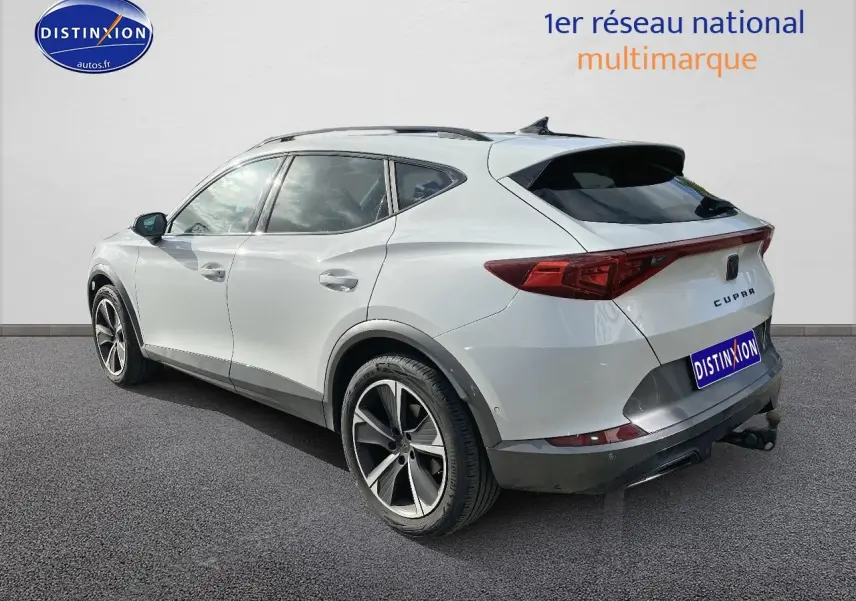 Vue 3/4 arrière droite d'un CUPRA Formentor blanc avec jantes alu et attelage visible sur fond neutre.