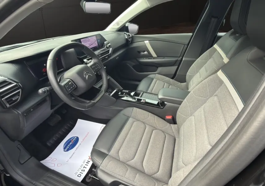 Intérieur avant droit de la Citroën C4 2023, sièges gris clair et noir avec tableau de bord et écran tactile.