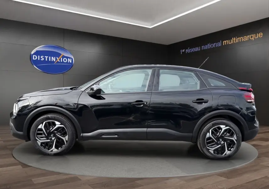 Profil côté gauche d'une Citroën C4 noire 2023 avec jantes distinctives et lignes fluides, en intérieur showroom.