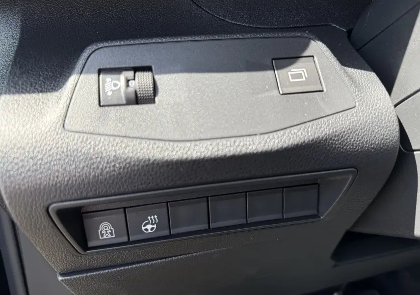 Détail intérieur du tableau de bord noir du Peugeot Rifter 2026, avec commandes de réglage des phares et du volant chauffant.
