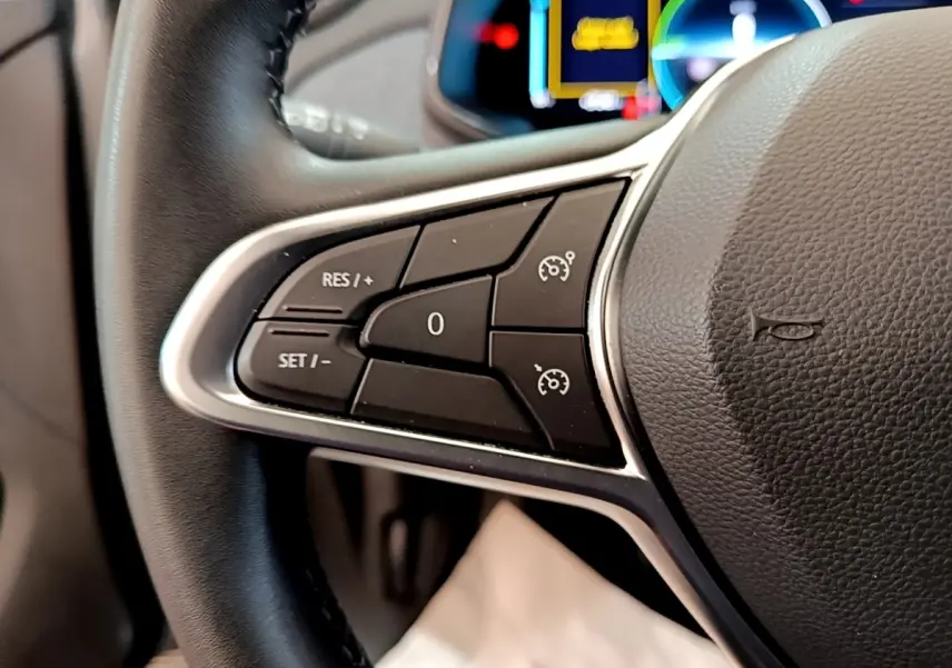 Gros plan sur les commandes de régulateur de vitesse au volant de la Renault ZOE gris clair 2022.