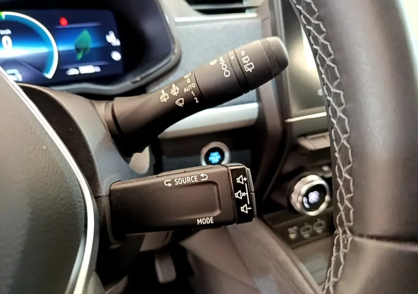 Vue rapprochée du volant et des commandes de la Renault ZOE gris clair, avec tableau de bord digital en arrière-plan.