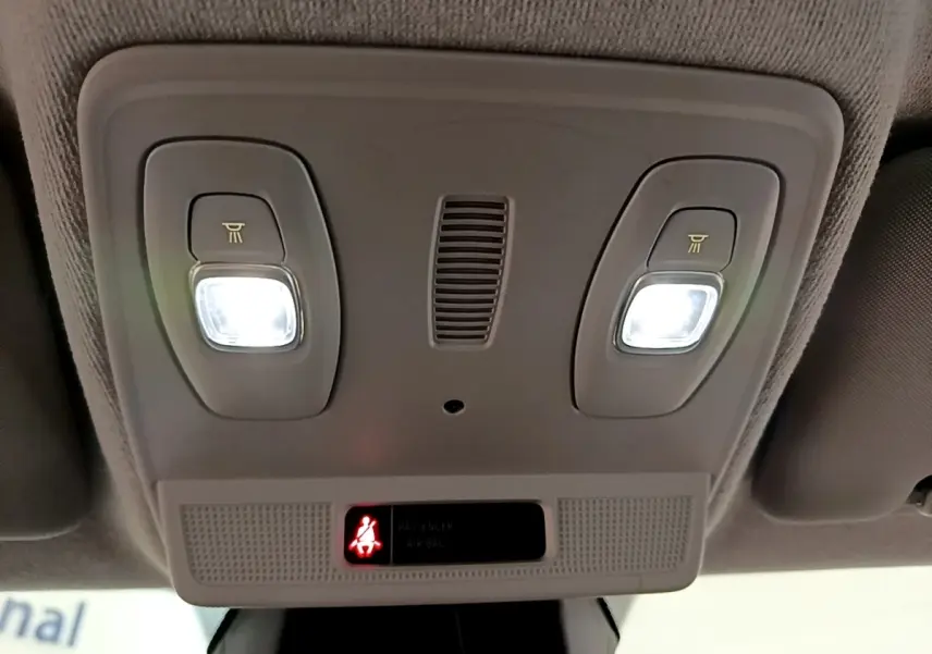 Plafonnier intérieur allumé avec deux lampes de lecture et témoin de ceinture de sécurité dans une Renault ZOE gris clair.