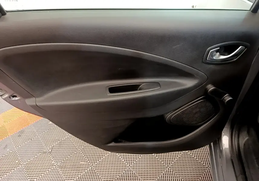 Vue intérieure du panneau de porte avant droit de la Renault ZOE gris clair, avec poignée et haut-parleur intégrés.