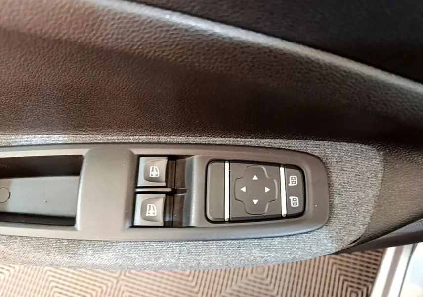 Détail des commandes de réglage des rétroviseurs et des vitres électriques sur la porte côté conducteur d’une Renault ZOE gris clair.