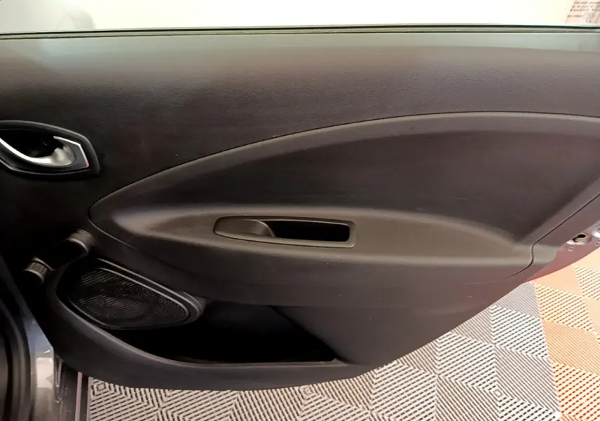 Vue rapprochée de la porte intérieure côté conducteur de la Renault ZOE gris clair, avec poignée et haut-parleur intégrés.