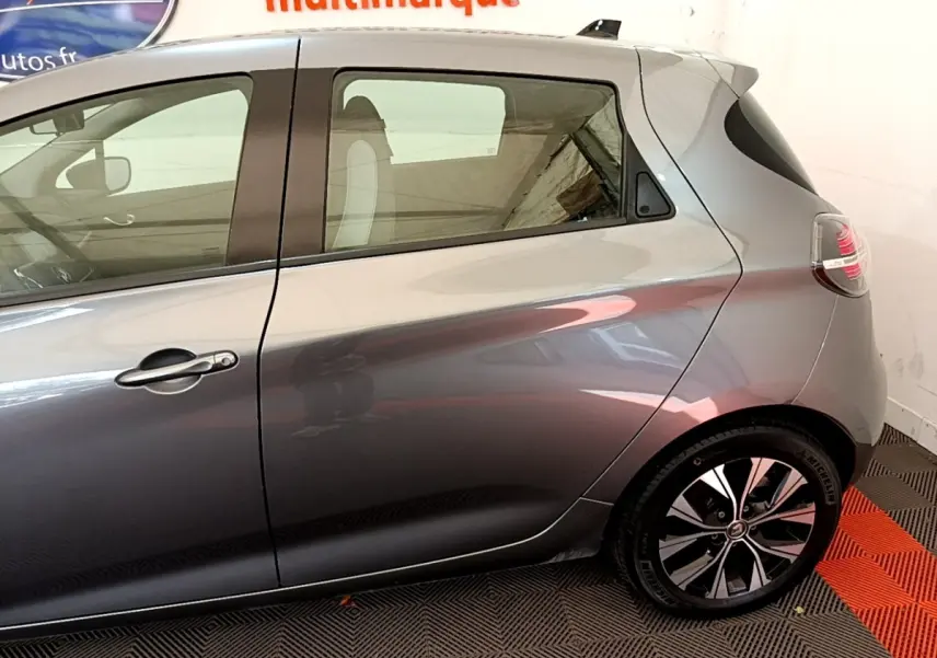 Profil droit de la Renault ZOE gris clair 2022 montrant la porte arrière et la jante au design moderne.