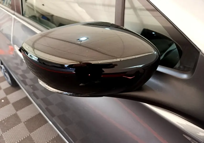 Rétroviseur noir en gros plan côté gauche sur Renault ZOE gris clair, finition électrique et moderne.