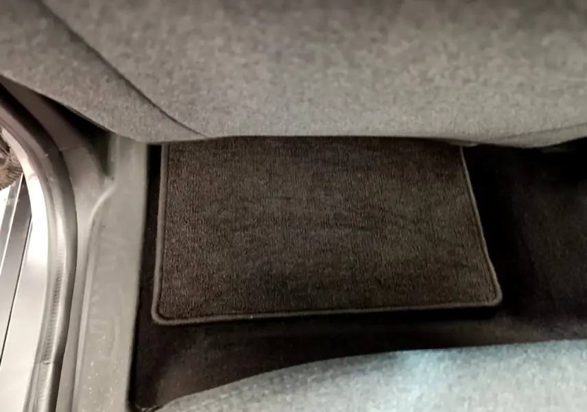 Détail du tapis de sol gris foncé sous le siège conducteur d'une Renault ZOE gris clair 2022 électrique.