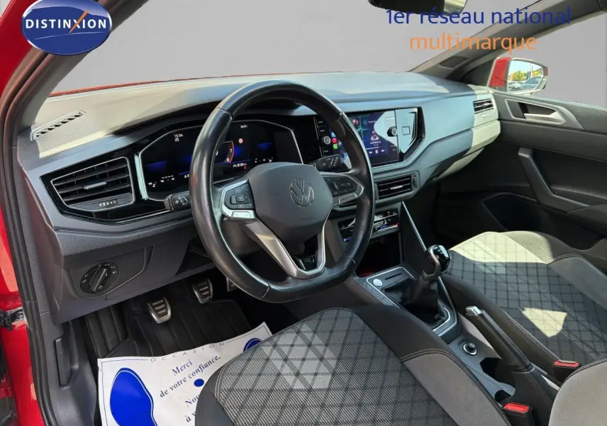 Vue intérieure côté conducteur de la Volkswagen Polo rouge Roi 2023, volant multifonction et tableau de bord numérique.