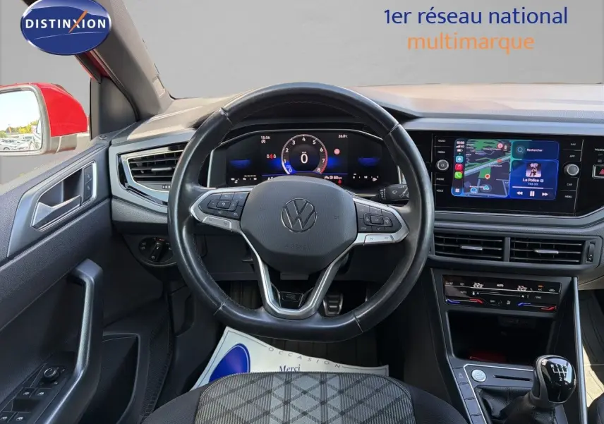 Vue intérieure centrée sur le volant et tableau de bord d’une Volkswagen Polo rouge Roi 2023, boîte manuelle visible.