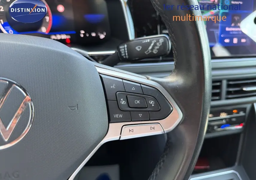 Gros plan sur le volant multifonction noir de la Volkswagen Polo 2023 avec commandes intégrées, tableau de bord en arrière-plan flou.