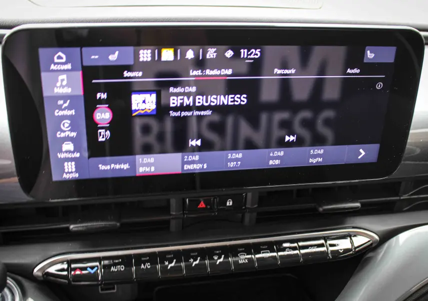 Écran tactile central de la FIAT 500 électrique 2023 affichant la radio DAB BFM Business, avec commandes climatisation en dessous.