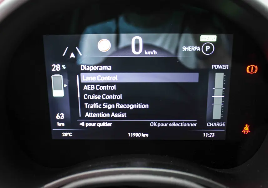 Tableau de bord numérique de la Fiat 500 électrique 2023 affichant les aides à la conduite et l'autonomie restante.