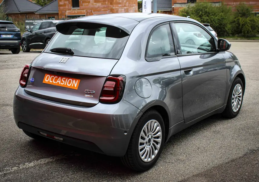 Vue 3/4 arrière droite d'une FIAT 500 électrique gris minéral métal avec feux arrière foncés et jantes stylisées.