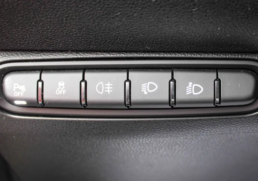 Gros plan sur les boutons de commande d’éclairage et d’assistance de la FIAT 500 électrique 2023, intérieur noir.