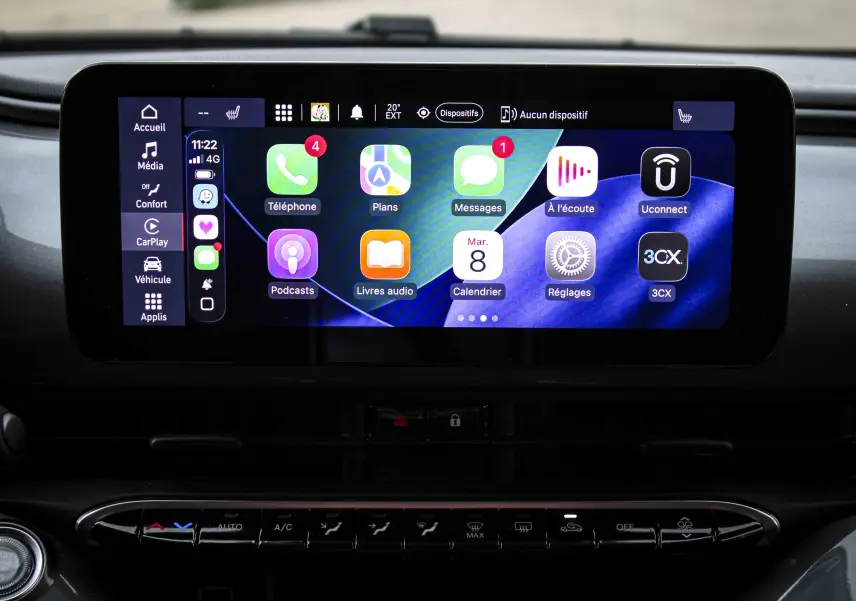 Écran tactile central de la Fiat 500 électrique 2023 affichant l'interface CarPlay avec icônes colorées, vue frontale intérieure.