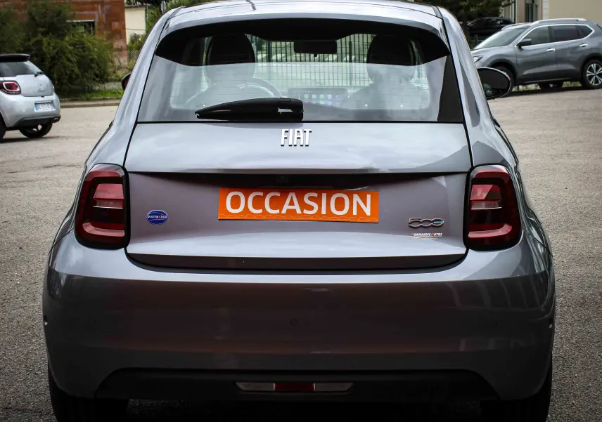 Vue arrière d'une FIAT 500 électrique gris minéral métal avec plaque orange "OCCASION" en extérieur.
