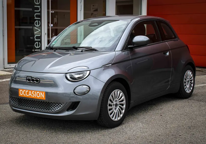 Fiat 500 électrique gris minéral métal vue 3/4 avant, avec calandre épurée et jantes multibranches.