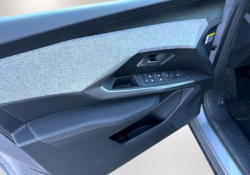 Vue rapprochée de la porte avant gauche du Peugeot 5008 gris artense, montrant les commandes des vitres et le revêtement tissu et cuir.