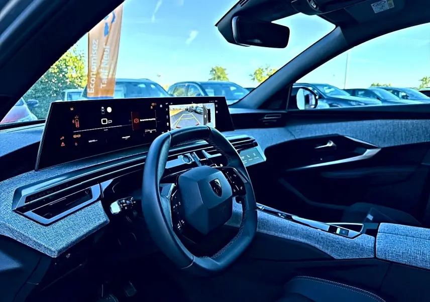 Vue intérieure côté conducteur du Peugeot 5008 Hybrid 145 allure e-dcs6 2025, tableau de bord et volant cuir multifonction.