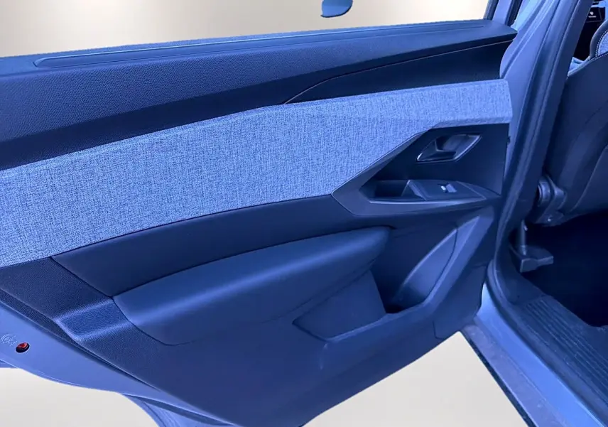 Vue rapprochée de la porte arrière gauche du Peugeot 5008 gris artense, avec insert tissu clair et commandes de vitre.