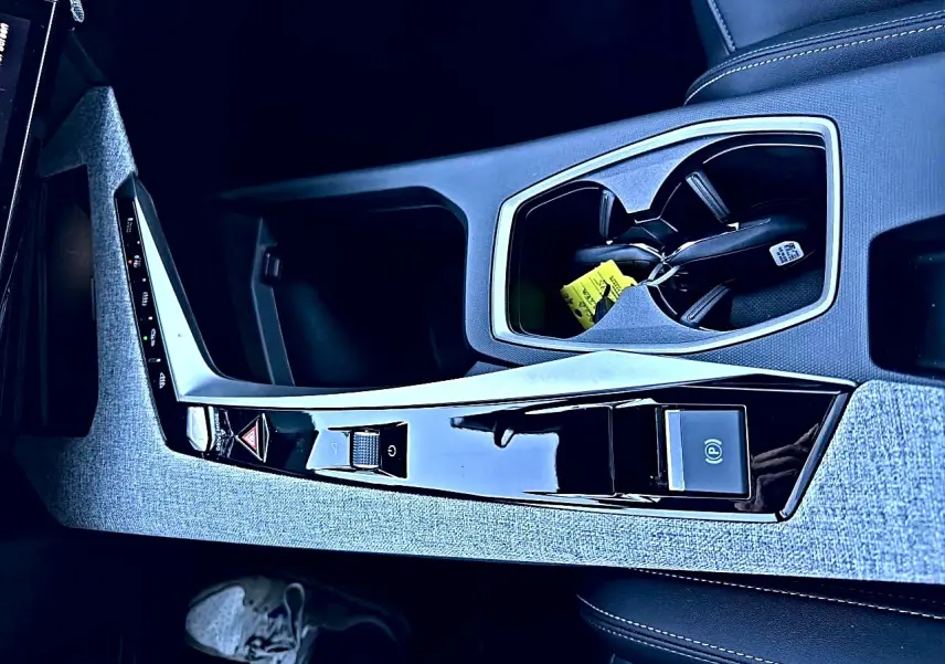 Vue rapprochée de la console centrale grise et noire du Peugeot 5008 Hybrid 145 allure e-dcs6 avec porte-gobelets et commandes.