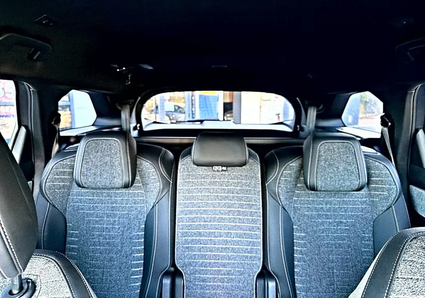 Vue intérieure arrière des sièges gris artense du Peugeot 5008 Hybrid 145 allure e-dcs6 avec appuis-tête et ceintures visibles.