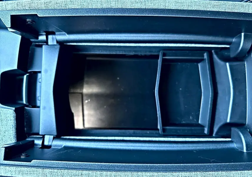 Vue rapprochée de l'accoudoir central ouvert du Peugeot 5008 gris Artense, montrant le rangement intérieur noir.