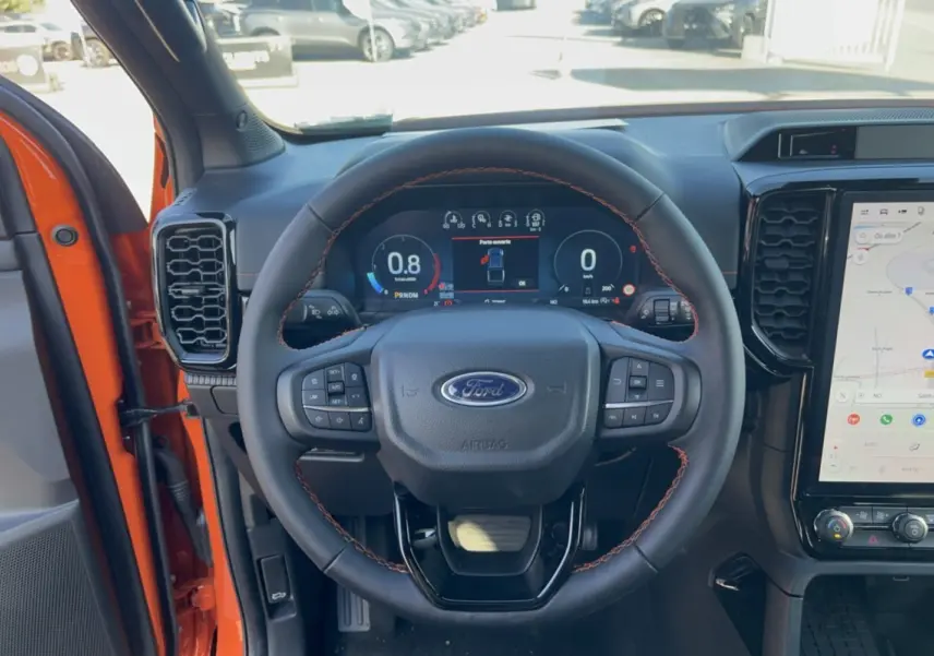 Vue intérieure centrée sur le volant cuir noir avec surpiqûres orange du Ford Ranger Wildtrak 2026 Ignite Orange.