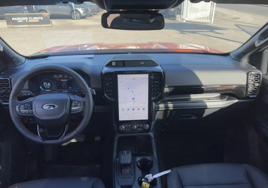 Vue intérieure avant du Ford Ranger Wildtrak 2026 avec tableau de bord noir, écran tactile vertical et volant cuir multifonctions.