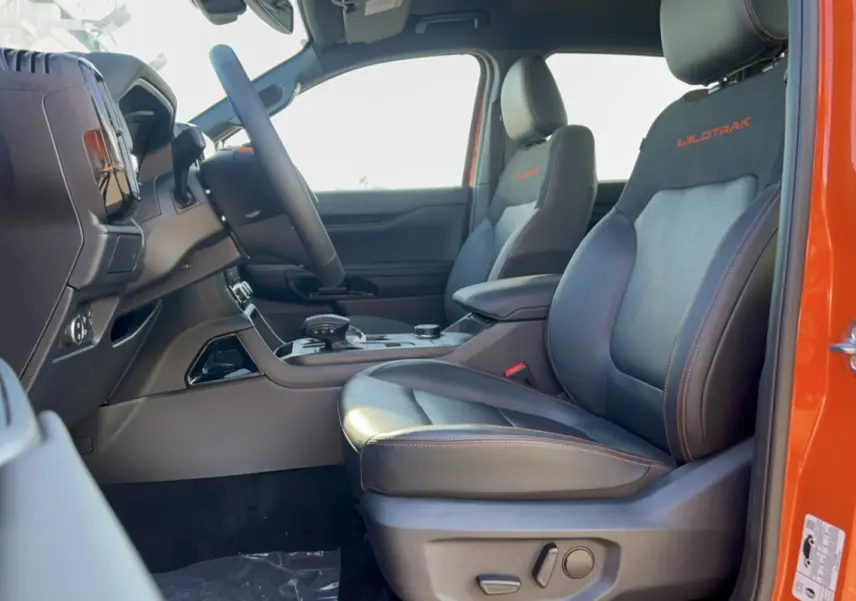 Vue intérieure côté droit du Ford Ranger Wildtrak orange, sièges cuir noirs avec surpiqûres orange et logo brodé.