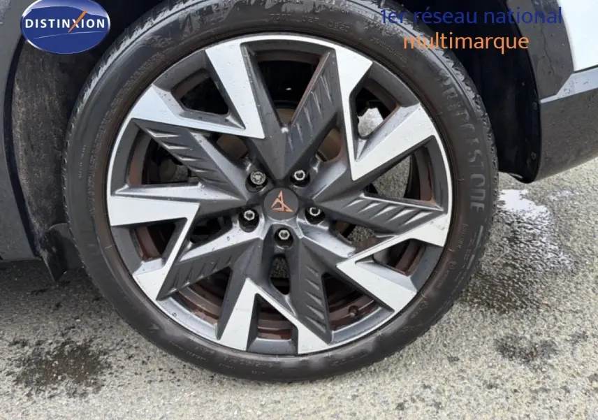 Gros plan sur la jante bi-ton gris et argentée du côté avant droit d'une CUPRA Formentor blanc neige métal.