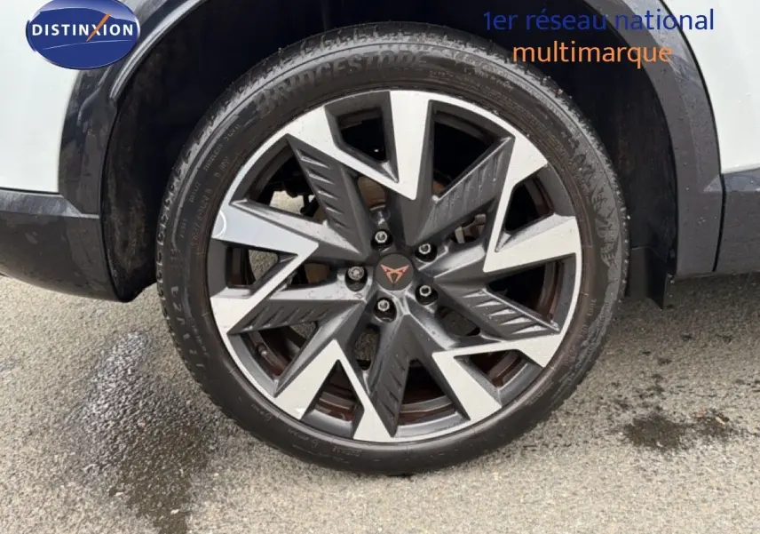 Gros plan sur la roue avant droite du CUPRA Formentor blanc neige métal, mettant en valeur la jante bi-ton au design anguleux.