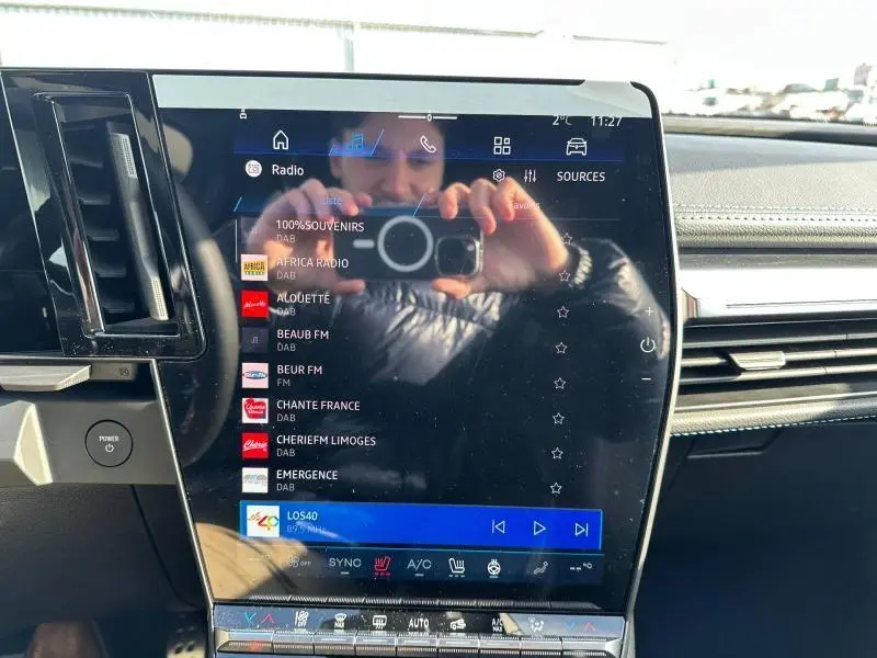 Vue rapprochée de l'écran tactile central du tableau de bord du Renault Scenic E-Tech gris Schiste, affichant les stations radio.