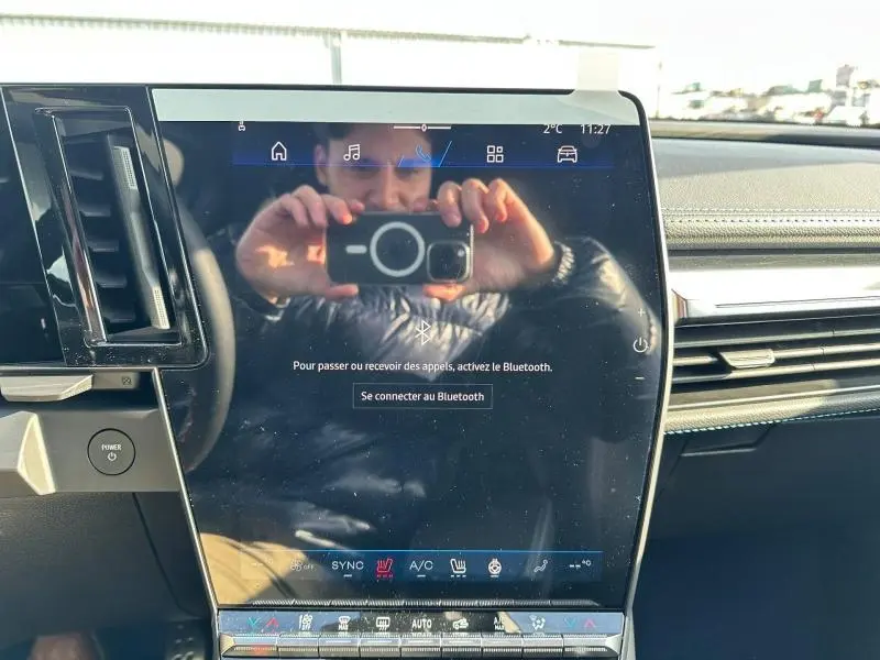 Vue rapprochée de l’écran tactile central du Renault Scenic E-Tech Electric gris, avec commandes clim et multimédia visibles.