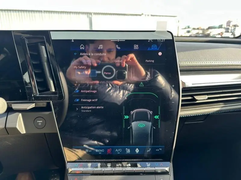 Vue rapprochée de l'écran tactile central du tableau de bord du Renault Scenic E-Tech gris Schiste, affichant les aides à la conduite.