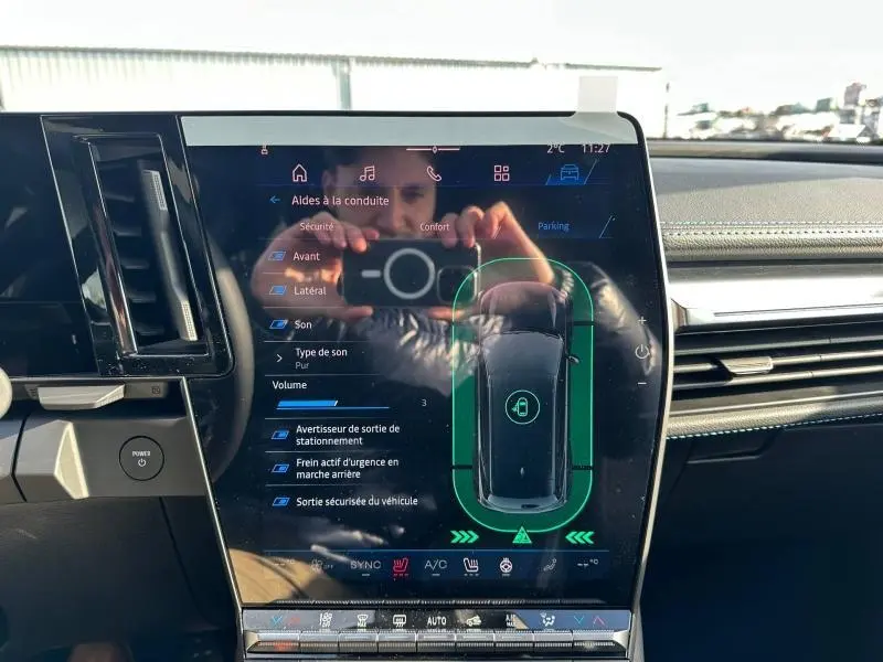 Écran tactile central du Renault Scenic E-Tech gris Schiste, affichant l'aide au stationnement et les réglages audio.